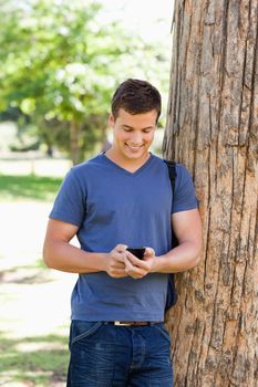 Muscled young man using a smartphone in a park