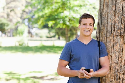 Portrait of a muscled young man with a smartphone in a park