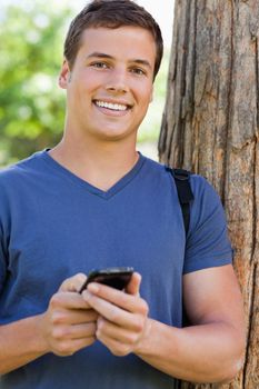 Portrait of a muscled student man using a smartphone in a park