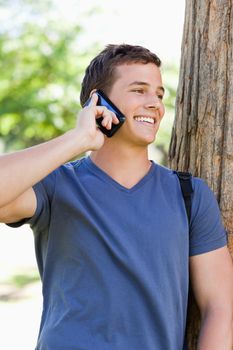Close-up of a smiling young man on the phone in a park