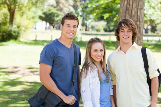 Portrait of smiling students with their bags in a park