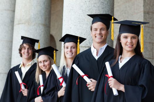 Portrait of graduates posing in single line with columns in background