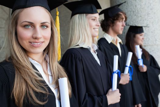 Close-up of a blonde graduate with blue eyes next to her friends posing