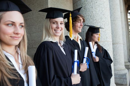 Blonde graduate next to her friends posing