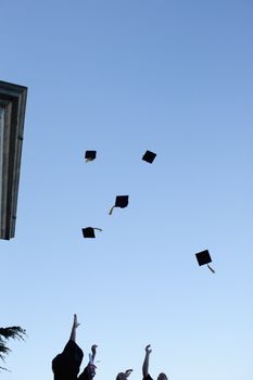 Low angle-shot of grad students throwing their hats in the sky 