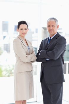 A mature director and his young secretary standing upright in front of the window