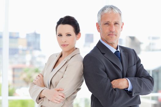 Serious business people standing upright in front of the window side by side