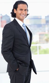 Businessman wearing a black suit and standing upright in a bright room