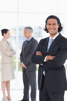 Smiling executive standing upright in front of two colleagues