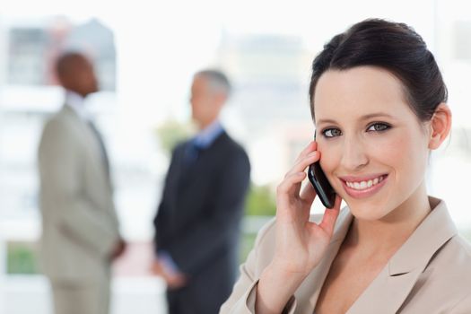 Young smiling secretary talking on the phone while looking at the camera