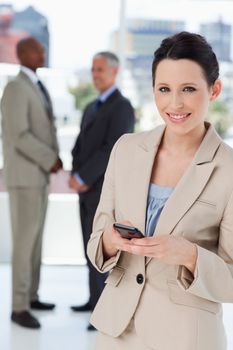 Smiling secretary standing in front of executives while sending a text