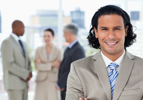 Smiling businessman looking at the camera in front of his team