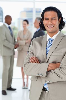 Young smiling businessman standing upright while crossing his arms
