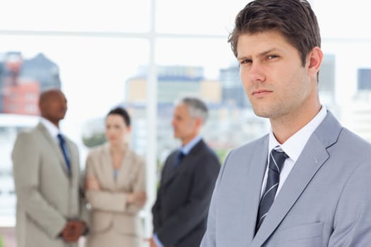 Young businessman with a stern look standing in front of executives