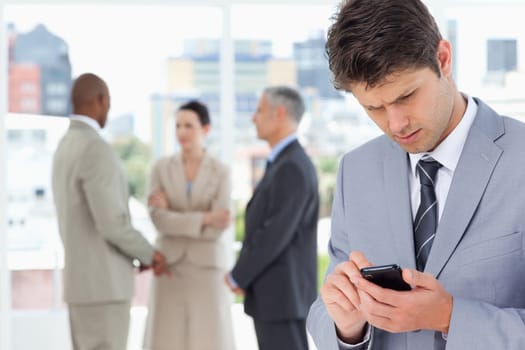 Young serious executive using his mobile phone to send a text