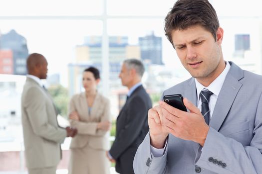 Serious manager sending a text with his mobile phone 