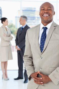 Young executive laughing while standing upright and crossing his hands