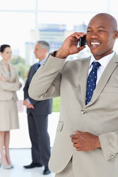 Manager laughing on the phone while his team is in the background