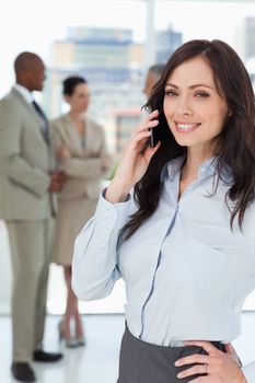 Smiling executive woman talking on the mobile phone with one hand on her hip