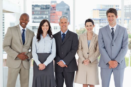 Business team smiling and standing upright side by side with their hands crossed