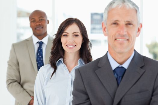 Three smiling executives standing upright and looking ahead