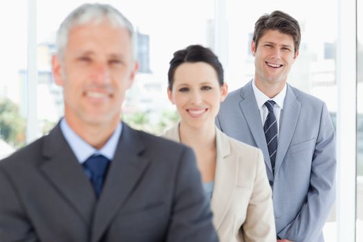 Young smiling executive standing behind two business people