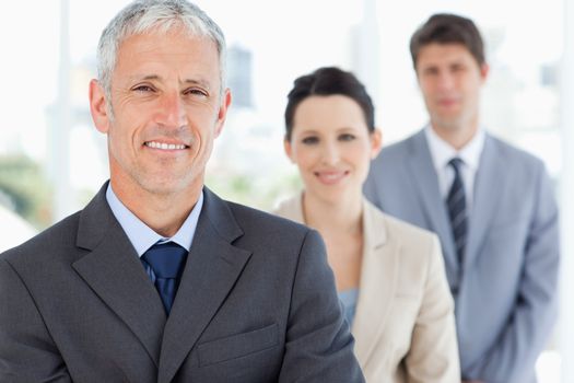 Mature smiling manager followed by two young business people