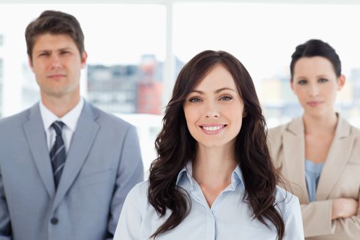 Young smiling woman standing in front of two business people