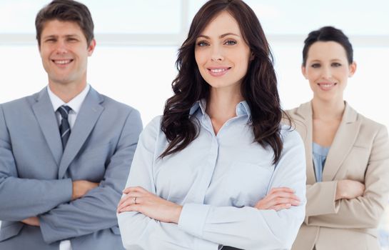 Young smiling executive woman crossing her arms in front of co-workers