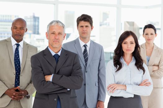 Business team seriously looking at the camera while standing in front of a window