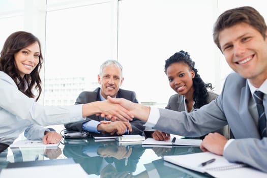 Young smiling executives shaking hands while looking at the camera