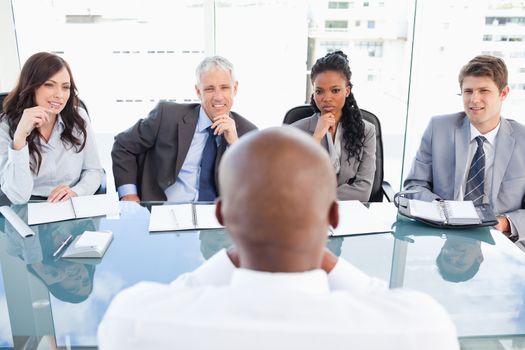 Four serious business people sitting at the desk while listening to explanations