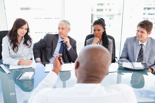 A manager and an employee communicating during a meeting with the full team