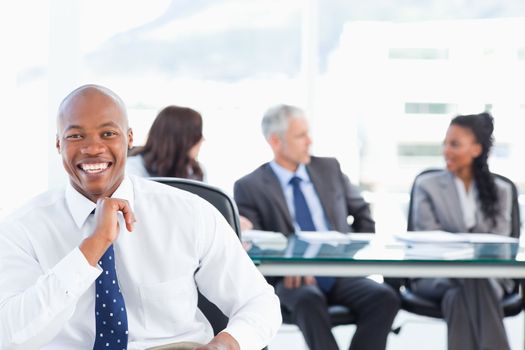 Executive laughing while looking at the camera with his team in the background