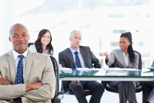 Young executive almost smiling in front of his team which is sitting in the back