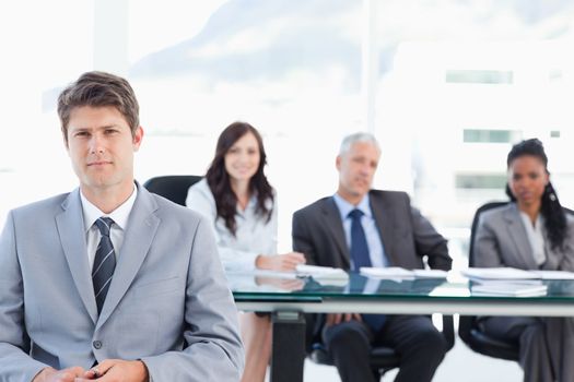 Earnest businessman sitting in front of his team in a well-lit room