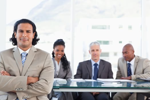 Stern executive crossing his arms while his team are behind him are looking at him