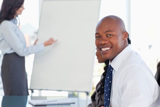 Young smiling executive wearing a white shirt and sitting at a desk in a meeting room