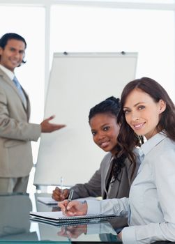 Young smiling employees working during a presentation and writing in a notebook