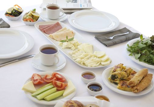 Breakfast table with cheese, tomatoes, olives, cucumber and pastries