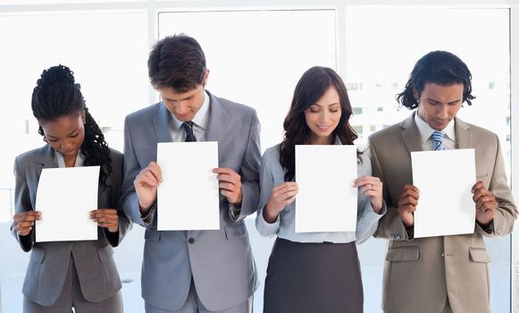 Young business people showing blank sheets while bowing their heads