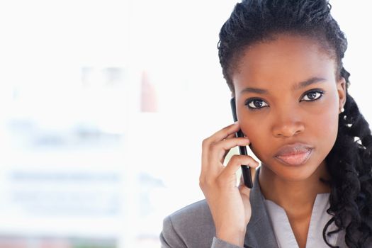 Young serious businesswoman looking straight ahead while talking on the phone