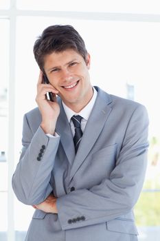 Smiling businessman crossing his arms while talking on the phone