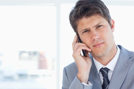 Young executive seriously calling somone in front of the window