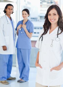 Young smiling female doctor standing upright with her hands in her pockets