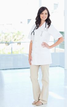 Confident and smiling nurse standing upright with one hand on her hip