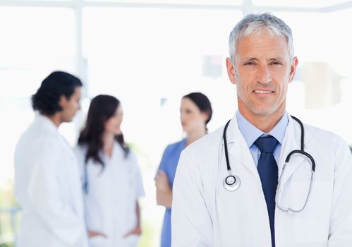 Mature doctor standing upright in front of his interns