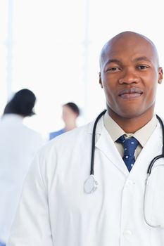 Young doctor grinning in front of his medical team with a confident look on his face