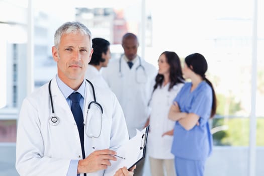 Mature doctor pointing seriously at something on his clipboard