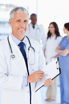 Mature doctor showing a great smile while pointing to a word on his clipboard